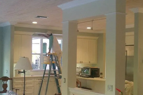 A person on a ladder in a kitchen painting walls